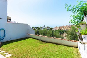 A fenced backyard with a grassy area and a view of a town.