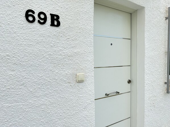 A white door with the number 69B on the wall above it.