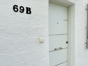 Eine weiße Tür mit der Nummer 69B über ihr an der Wand.