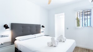 Un dormitorio moderno con una cama grande, lámparas de noche, una mesita de noche y un ventanal con vistas.