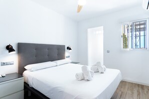 A modern bedroom with a large bed, bedside lamps, a nightstand, and a window with a view.