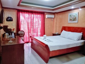 Relax in this inviting space with a large bed, a desk, and a comfortable chair.