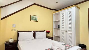 Quarto com cama, mesa de cabeceira, guarda-roupa e luminária no teto.