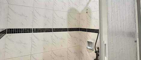 A shower with white marble tiles, a black tile border, and a showerhead.