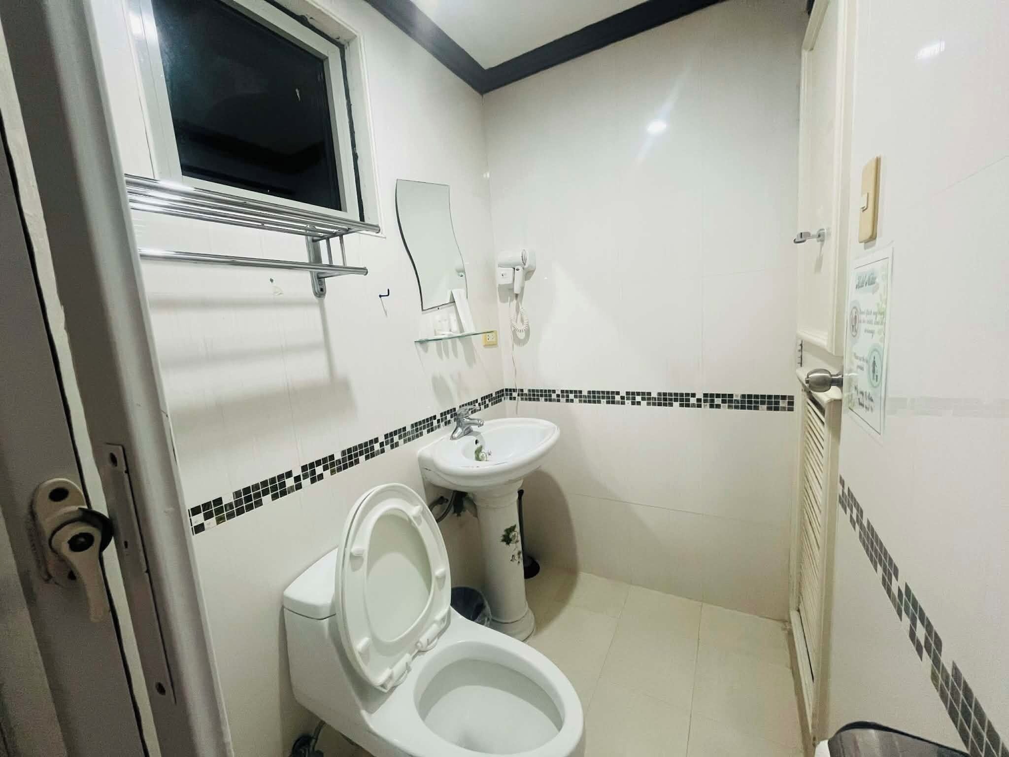 A bathroom with a toilet, sink, and window.