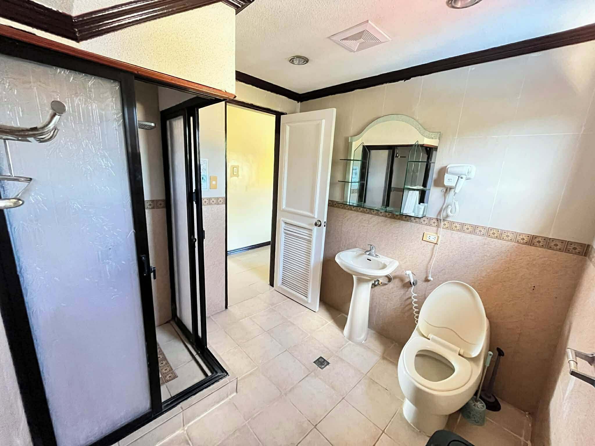 A bathroom with a toilet, sink, and shower area.