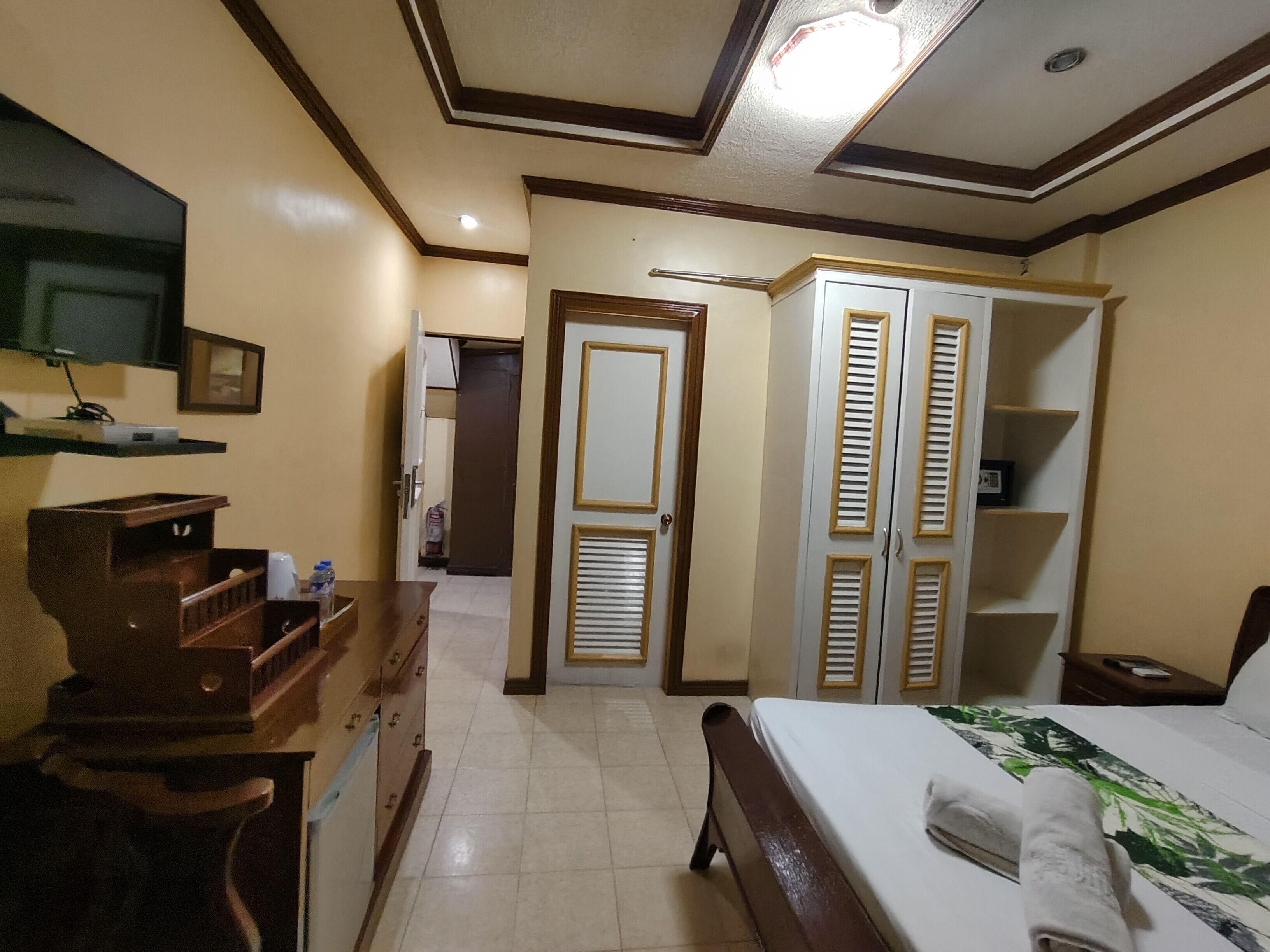 A hotel room with a bed, a wardrobe, a mirror, and a television.