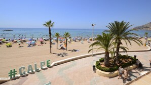 Una playa con palmeras, sombrillas y gente.