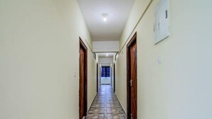 Un pasillo estrecho con suelo de baldosas y puertas de madera a ambos lados.
