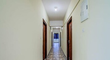 A narrow hallway with tiled flooring and wooden doors on both sides.