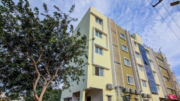 Un edificio de varios pisos con fachada amarilla, varias ventanas y unidades de aire acondicionado.