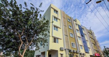 A multi-story building with a yellow facade, multiple windows, and air conditioning units.