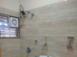 A bathroom with a shower, a toilet, and a window.