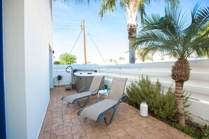 Un patio exterior con dos sillones, una mesita y un jacuzzi.