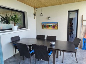 A dining area with a table and chairs, a potted plant, a painting, and hanging lights.