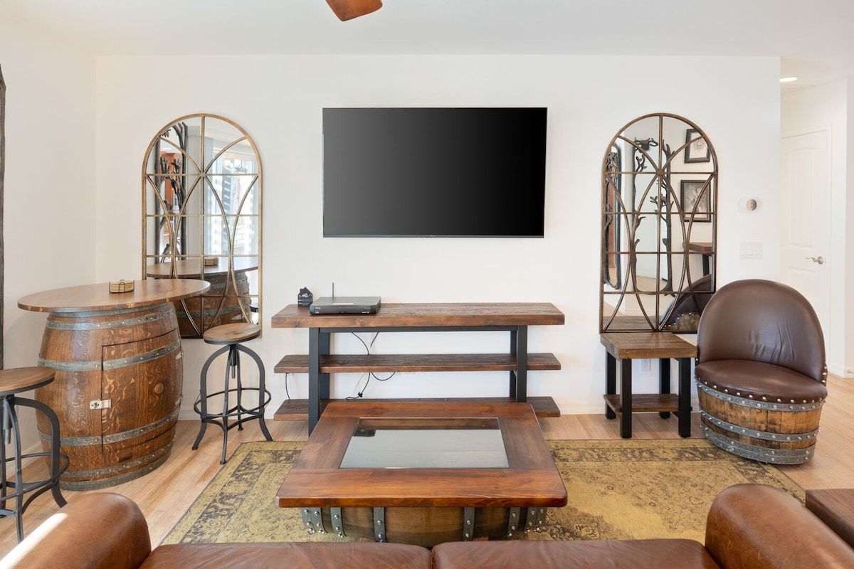 A living room with a flat-screen TV, wooden furniture, and decorative mirrors.