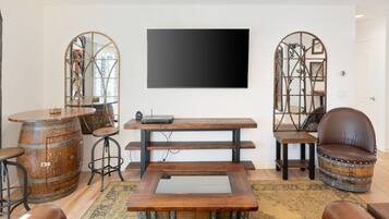 A living room with a flat-screen TV, wooden furniture, and decorative mirrors.