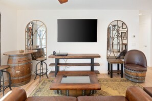 Una sala de estar con televisor de pantalla plana, muebles de madera y espejos decorativos.