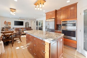 A modern kitchen with wooden cabinets, stainless steel appliances, and a granite countertop. - Of Wine & Gods - Hot Tub, BBQ and Fire Pit (Joshua Tree)