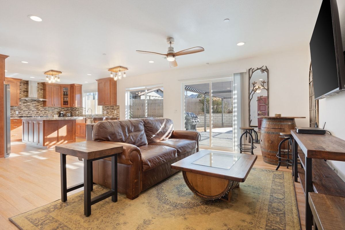 A modern kitchen with a stone island, a leather sofa, and a dining area with wooden tables and chairs.