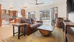 A modern kitchen with a stone island, a leather sofa, and a dining area with wooden tables and chairs.