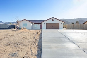 A residential house with a garage, a driveway, and a fenced yard. - Of Wine & Gods - Hot Tub, BBQ and Fire Pit (Joshua Tree)