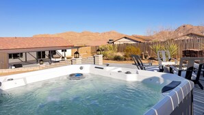 A hot tub with a wooden deck, surrounded by outdoor furniture and a wooden fence. - Of Wine & Gods - Hot Tub, BBQ and Fire Pit (Joshua Tree)