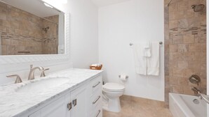 A bathroom with a white sink, a toilet, and a shower area.