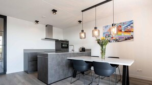 Una cocina moderna con una isla central, sillas negras y lámparas colgantes.