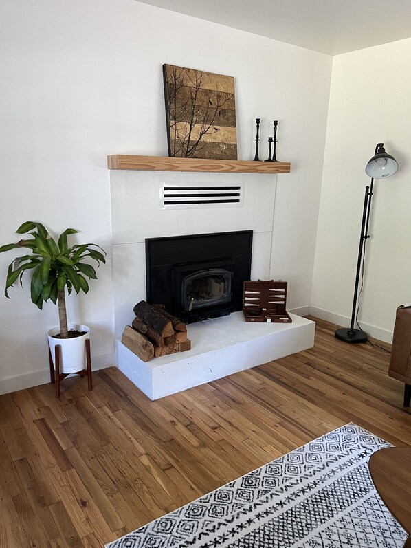 Una sala de estar moderna con chimenea, una planta en maceta, una alfombra estampada y una lámpara de pie alta.