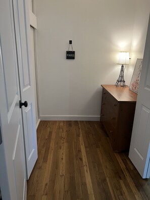 Une pièce avec un plancher en bois, un bureau avec des tiroirs, une lampe et un panneau portant l’inscription « PARIS » sur le mur.