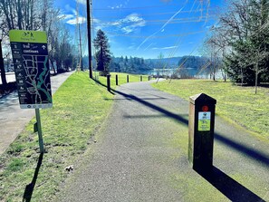 Un chemin bien défini mène à un panneau indiquant le début d’une piste cyclable, avec des indications sur le trajet à suivre.