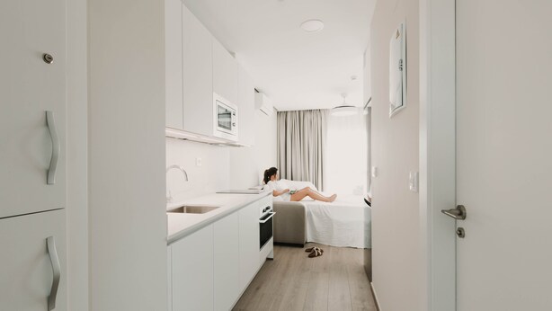 A modern, compact hotel room with a kitchenette, a bed, and a view of the city. - Apartamentos SubUp (Cartagena)