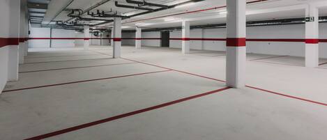 An indoor parking garage with white pillars and red lines marking parking spaces.