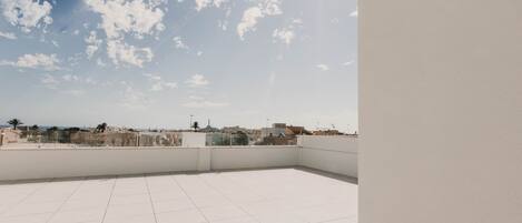 A rooftop terrace with a clear view of the city skyline and a tiled floor.