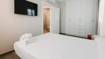 Habitación de hotel con cama, televisor montado en la pared, armario y unidad de aire acondicionado.
