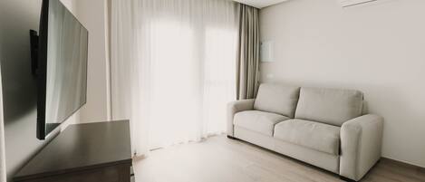 A modern living room with a flat-screen TV, a sofa, and a ceiling fan.