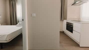 Een hotelkamer met een bed, een kitchenette en een badkamer met douchegordijn.