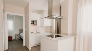 A modern kitchen with white cabinetry, a built-in microwave, and a stainless steel sink. - Apartamentos SubUp (Cartagena)
