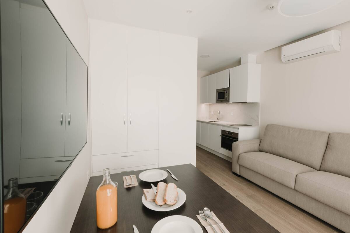 A modern kitchen with white cabinets, a microwave, and a dining area with a table set for two.