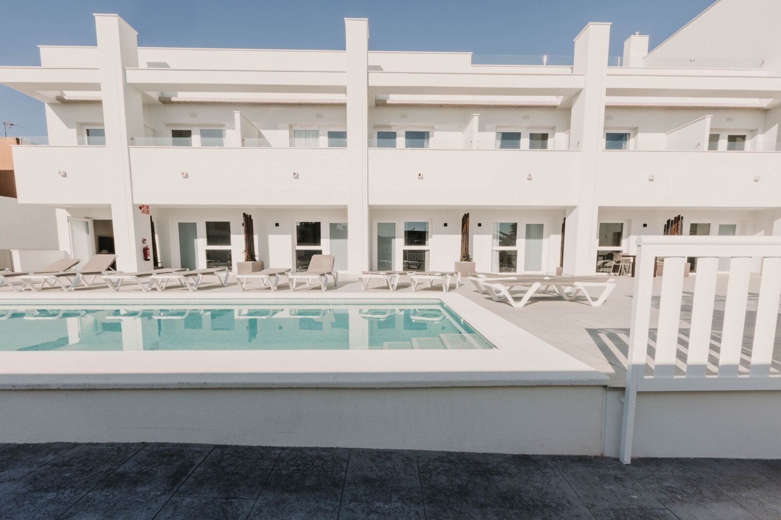 Un edifici modern amb una piscina i gandules.
