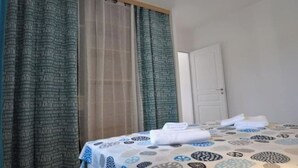 Ein Hotelzimmer mit Bett, einem Vorhang mit Städtenamen und einer Tür.