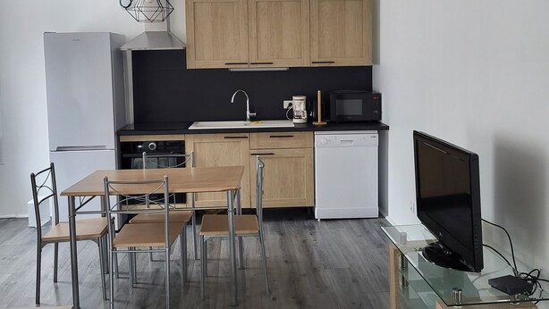 Une cuisine moderne avec des meubles en bois, un plan de travail noir et une table à manger en verre.