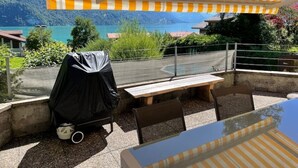Un espace extérieur aménagé avec des sièges, offrant une vue sur un lac et des montagnes.