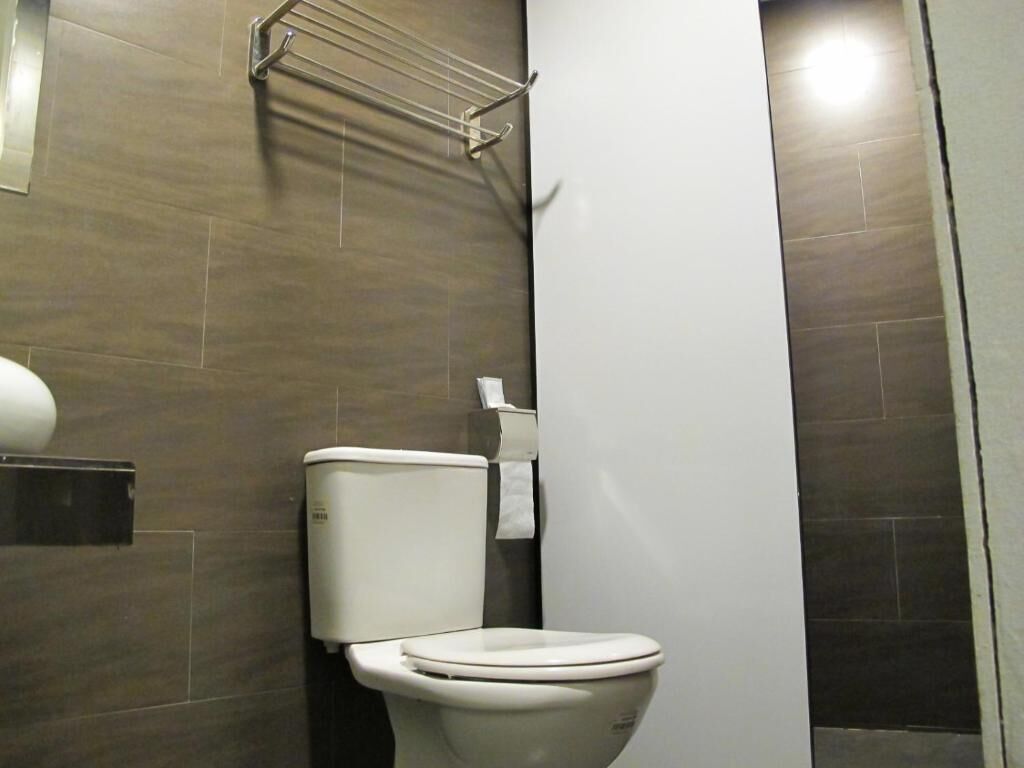 A modern bathroom with a toilet, a towel rack, and a wall-mounted toilet paper holder.