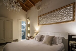 Camera da letto con un grande letto, un lampadario, soffitto in legno e pannello decorativo a parete.