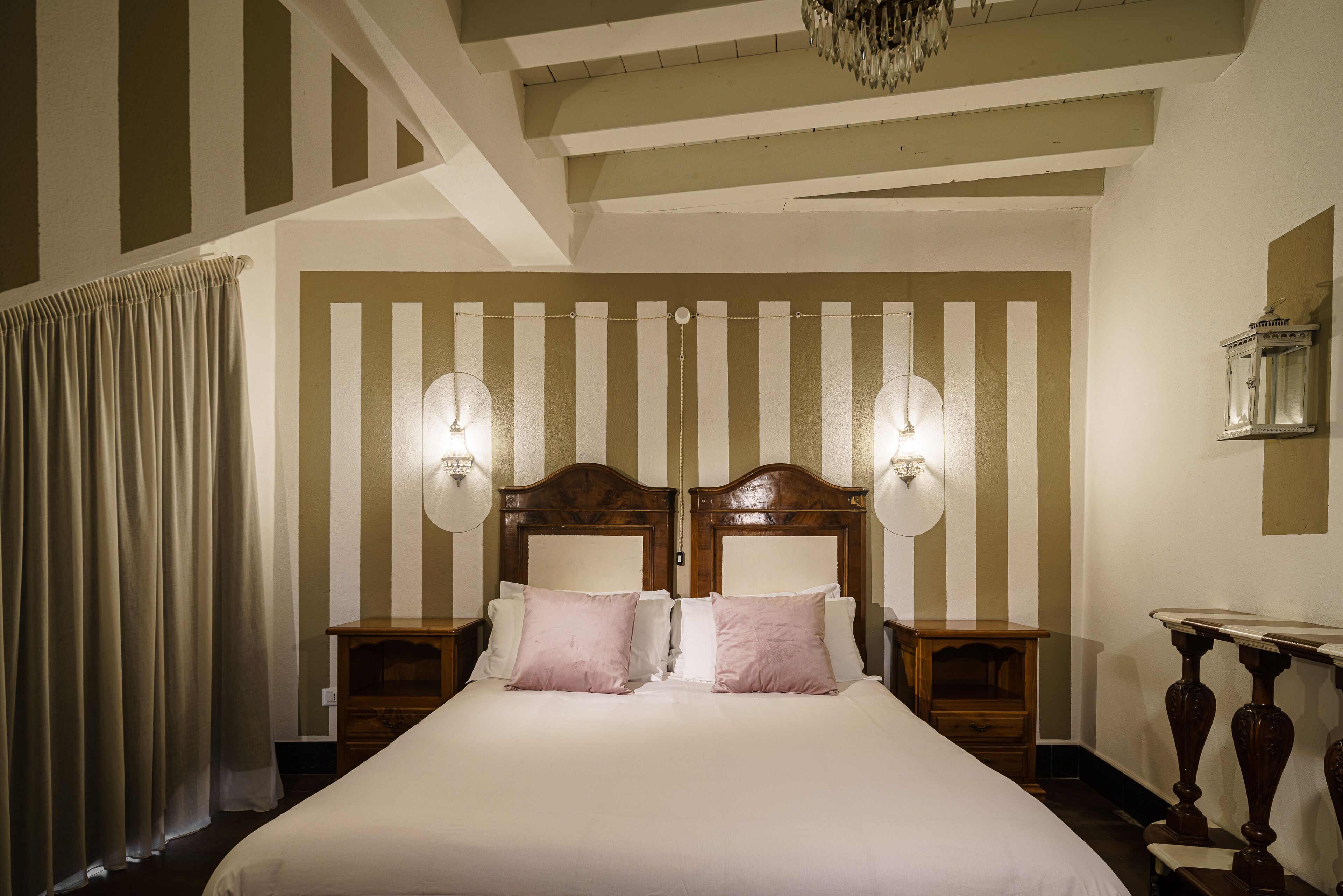 A large bed with a wooden headboard, two bedside tables, and two wall-mounted lamps.