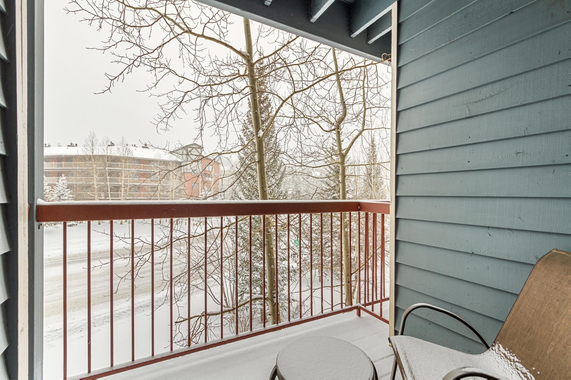 Ein Balkon mit Metallgeländer, einem Tisch und einem Stuhl.