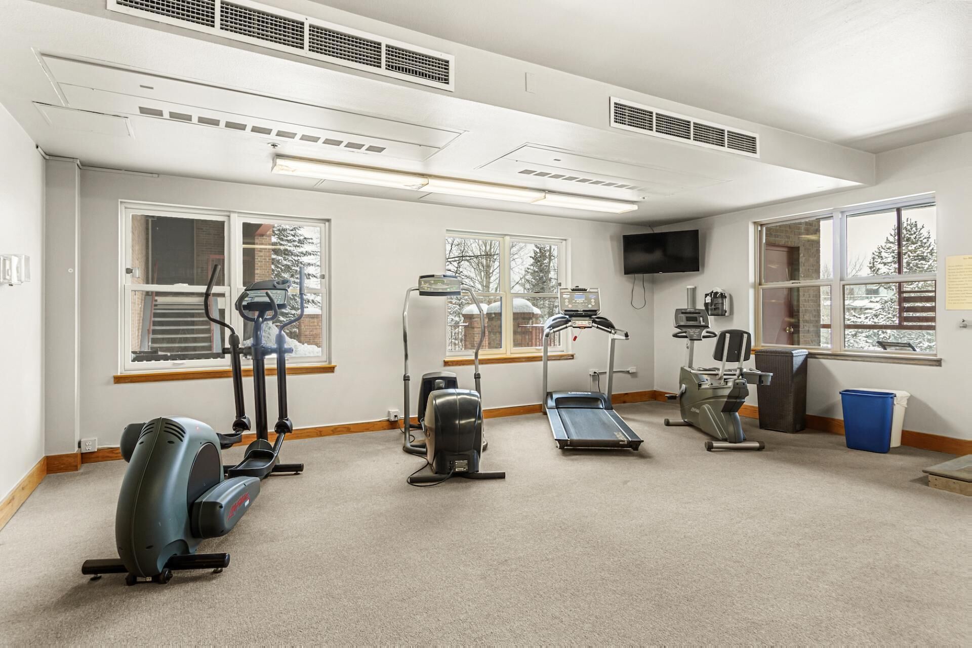 Een fitnessruimte met loopbanden, crosstrainers en een hometrainer.