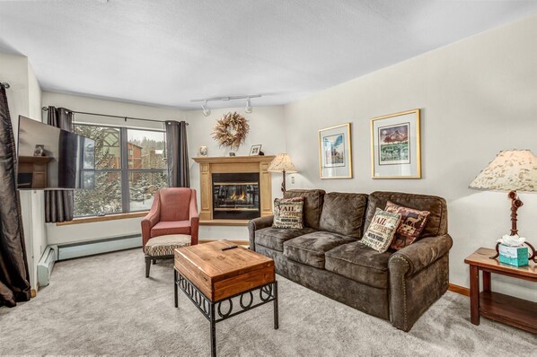A living room with a fireplace, a sofa, a chair, and a coffee table. - Ski-In Condo, Walk to Gondola | Hot Tubs (Breckenridge)